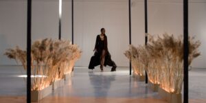 Model in a sleek minimalist look walking a runway in a calm, pared down setting