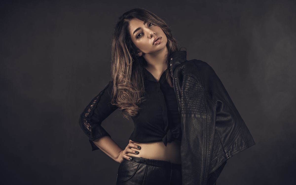 Stylish woman in a sleek black leather jacket in a moody studio portrait
