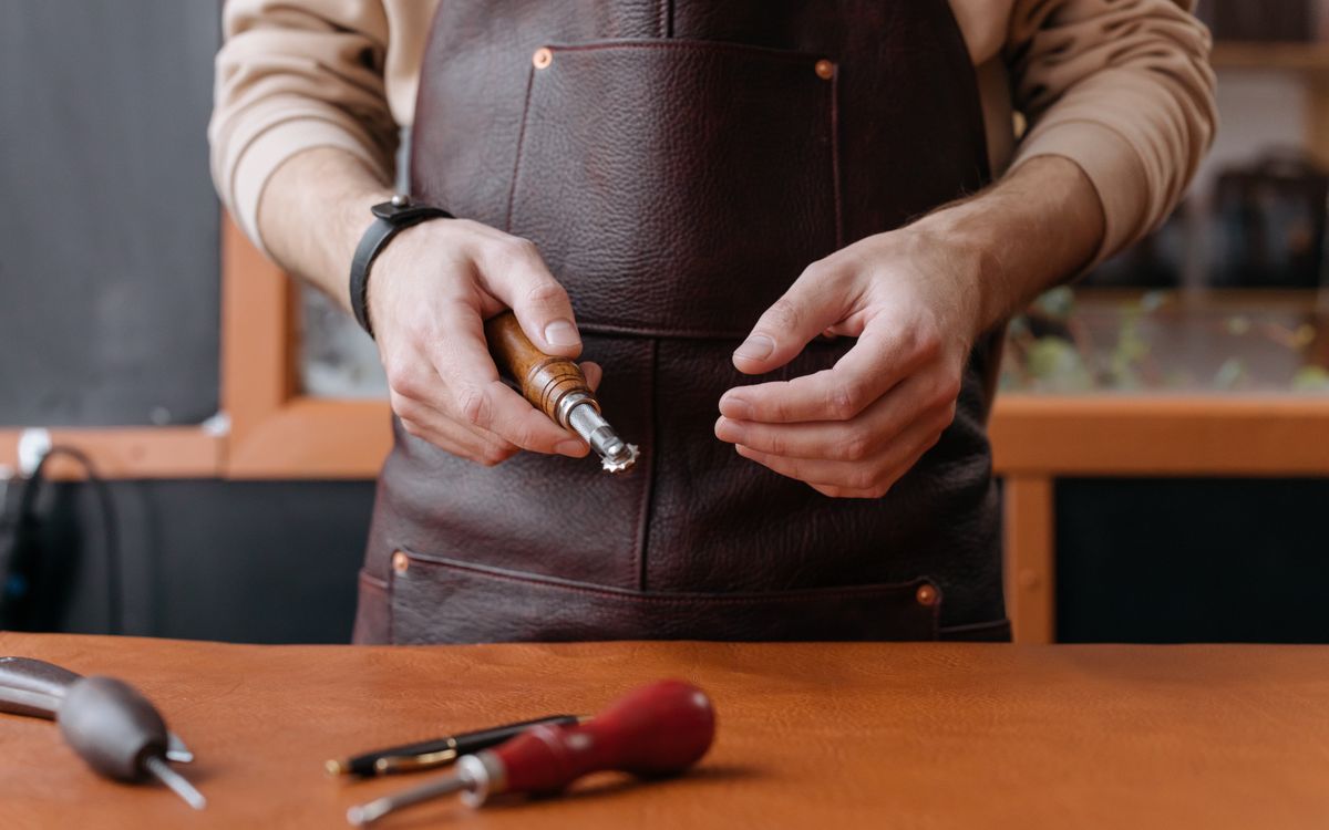 A craftsman shaping leather by hand with a traditional tool