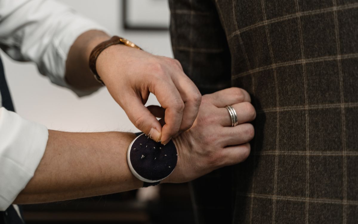 Close-up of a tailor adjusting a checkered suit jacket during a fitting session