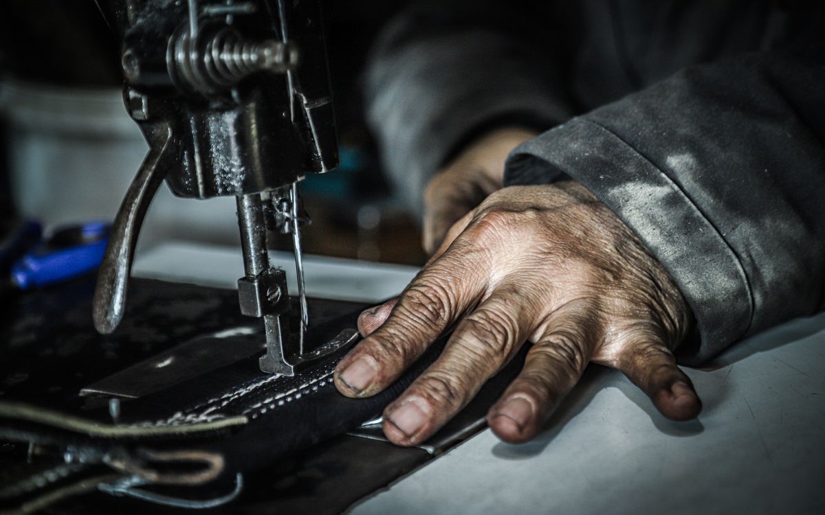 Hands guiding material through a sewing machine in a workshop