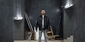 Confident man in a black leather jacket standing in an industrial space