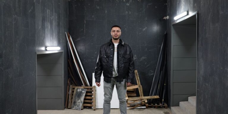 Confident man in a black leather jacket standing in an industrial space