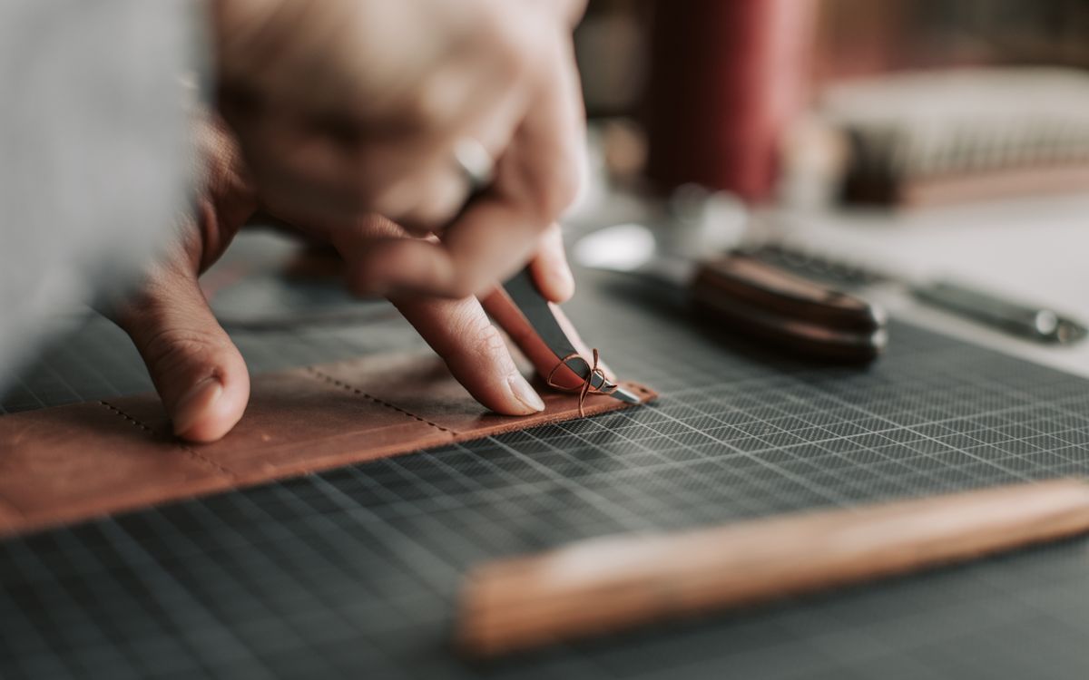 Close-up of hands intricately working on a leather piece in a crafting workshop