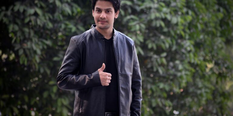 Confident man in a black leather jacket standing outdoors