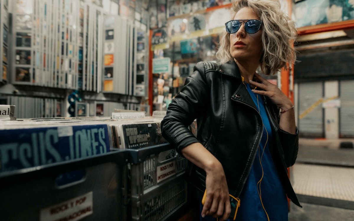 Fashionable woman in a leather jacket and sunglasses posing in a vinyl record store