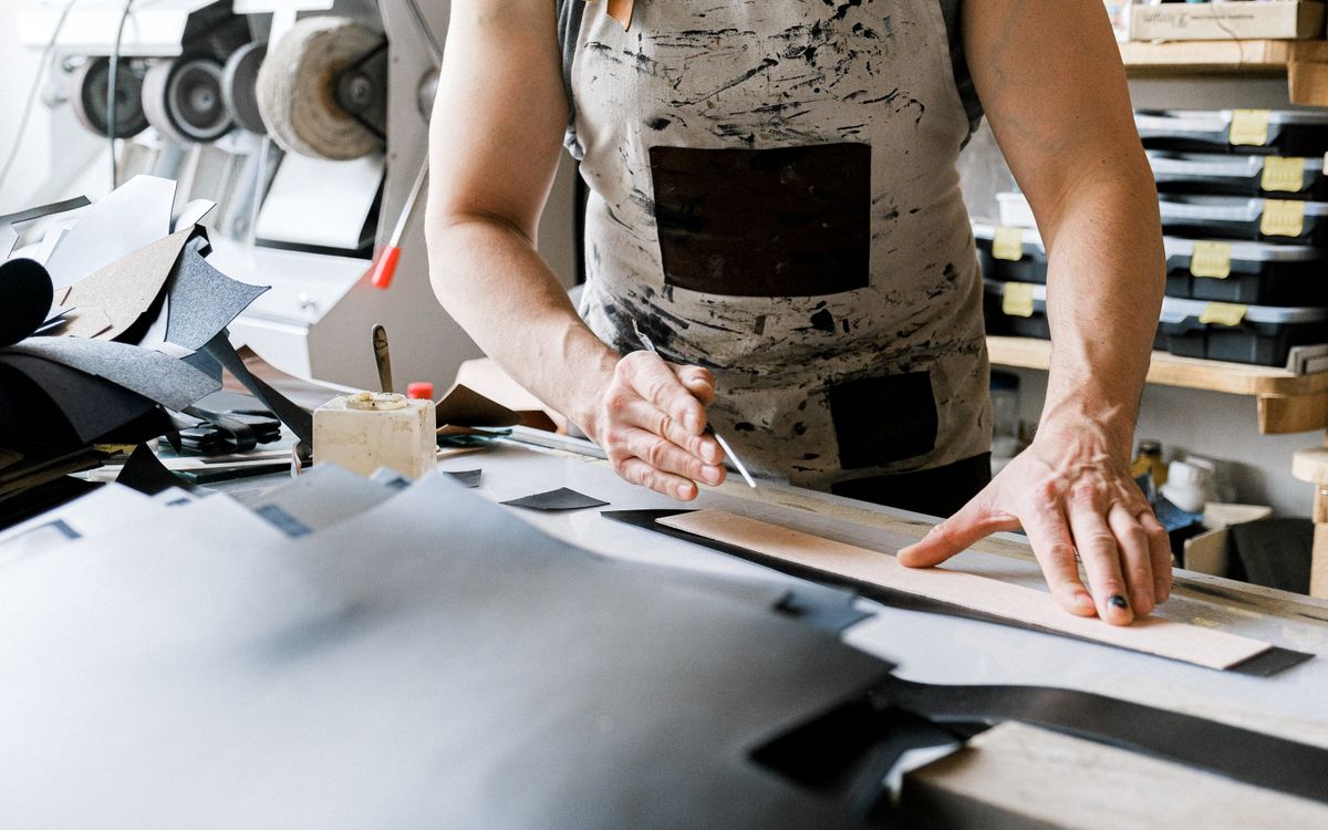 A leather artisan actively crafting a piece in a well-equipped workshop, showcasing detailed handiwork