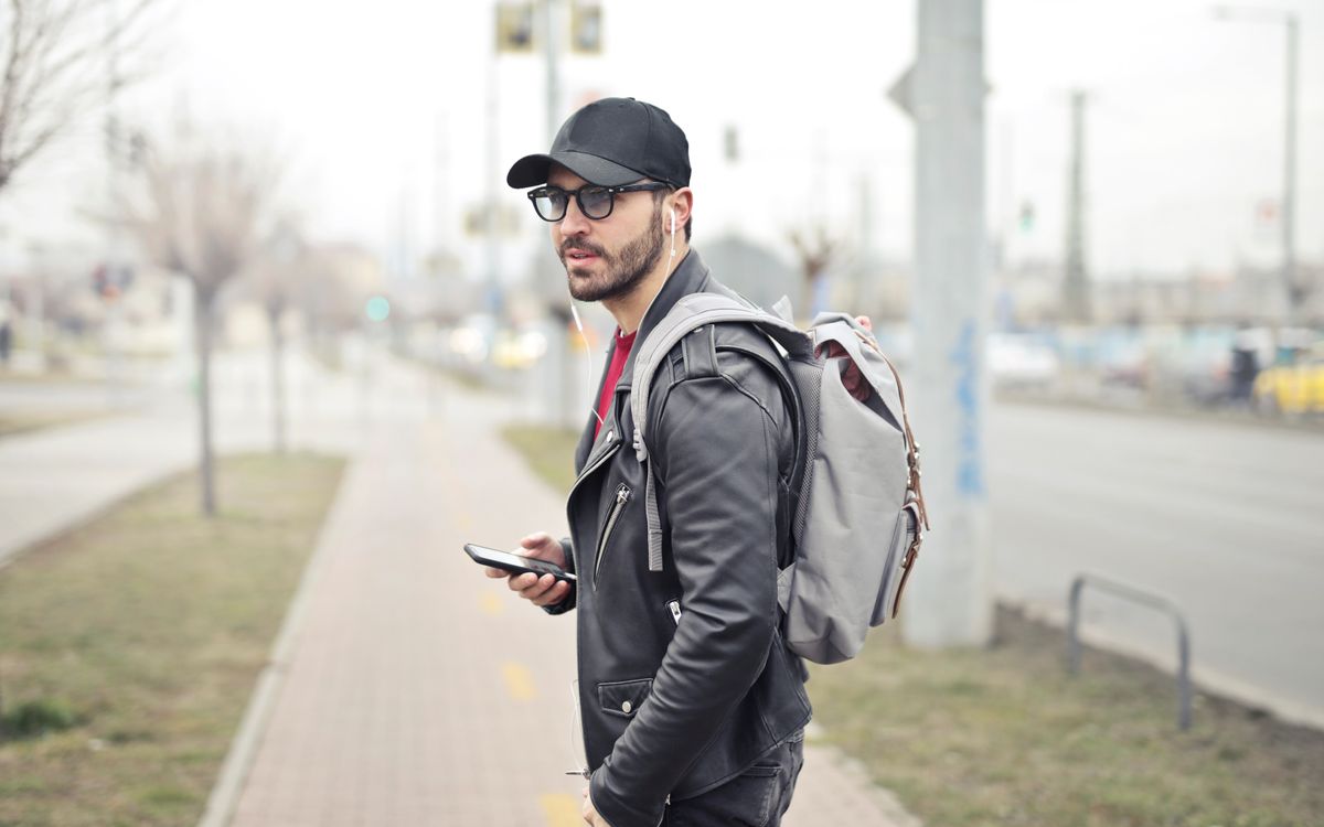 A fashionable young man in Budapest checking his smartphone on a busy street