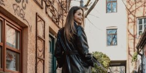 Fashionable woman in a long black leather coat walking a graffiti lined city street
