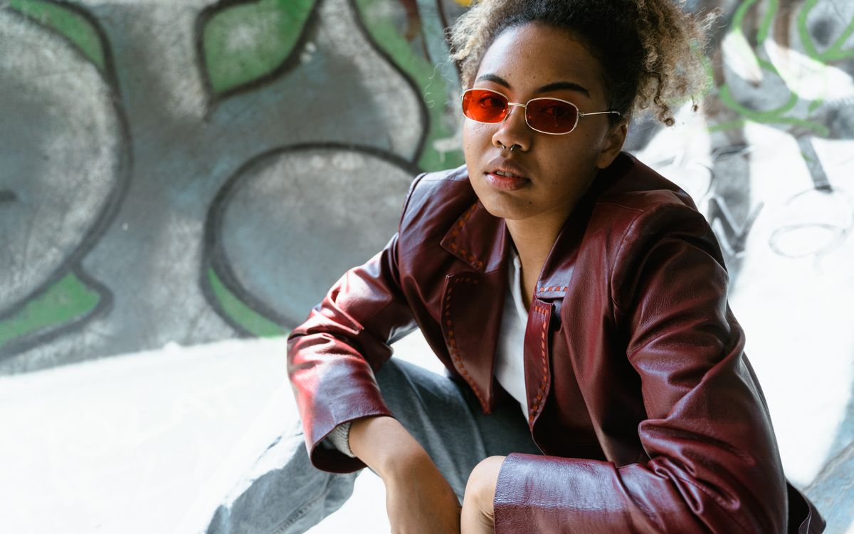 Portrait of a woman in a maroon leather jacket and red sunglasses in the city