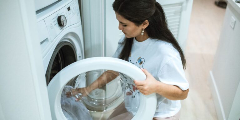 Close-up of hands loading clothes into a front-loading washing machine