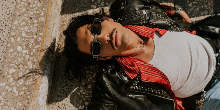 Man in a leather jacket relaxing outdoors on stone steps in warm sunlight