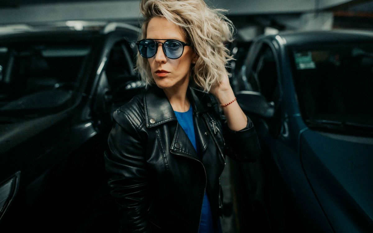 Stylish woman wearing a leather jacket, posing confidently in an urban setting