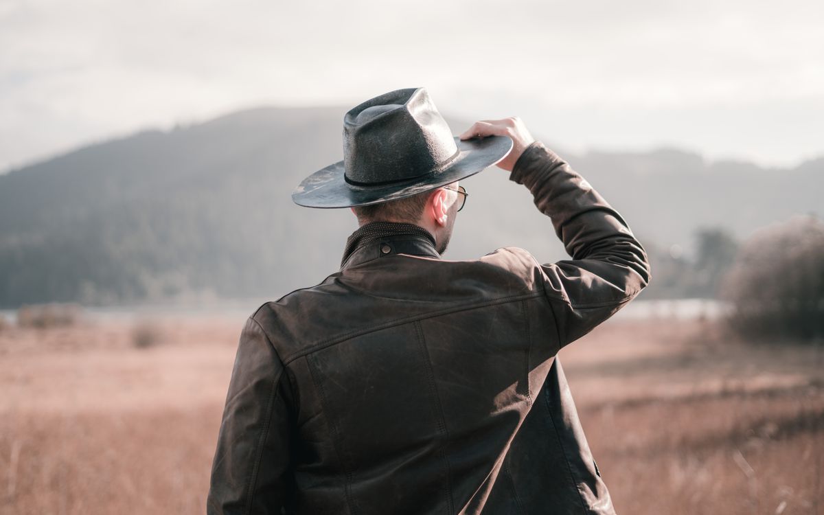 Man in a well maintained leather jacket standing outdoors on a scenic overlook