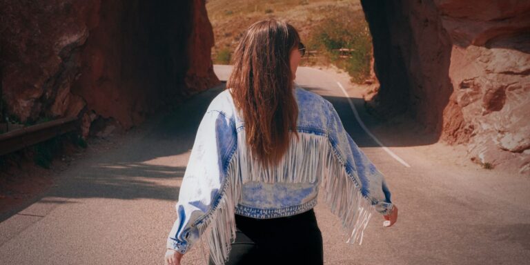 Woman in a fringed jacket walking through a picturesque stone tunnel on a sunny autumn day