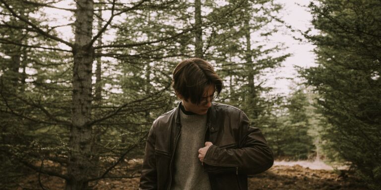 Man wearing a leather jacket in a peaceful forest setting