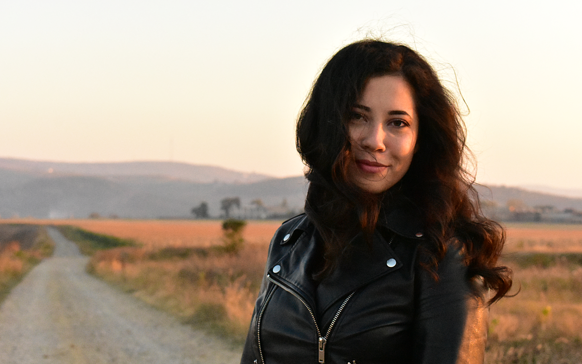 Woman in a black leather jacket on a rural road at sunset