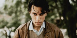 Portrait of a stylish young man wearing a leather jacket posing outdoors in a natural setting