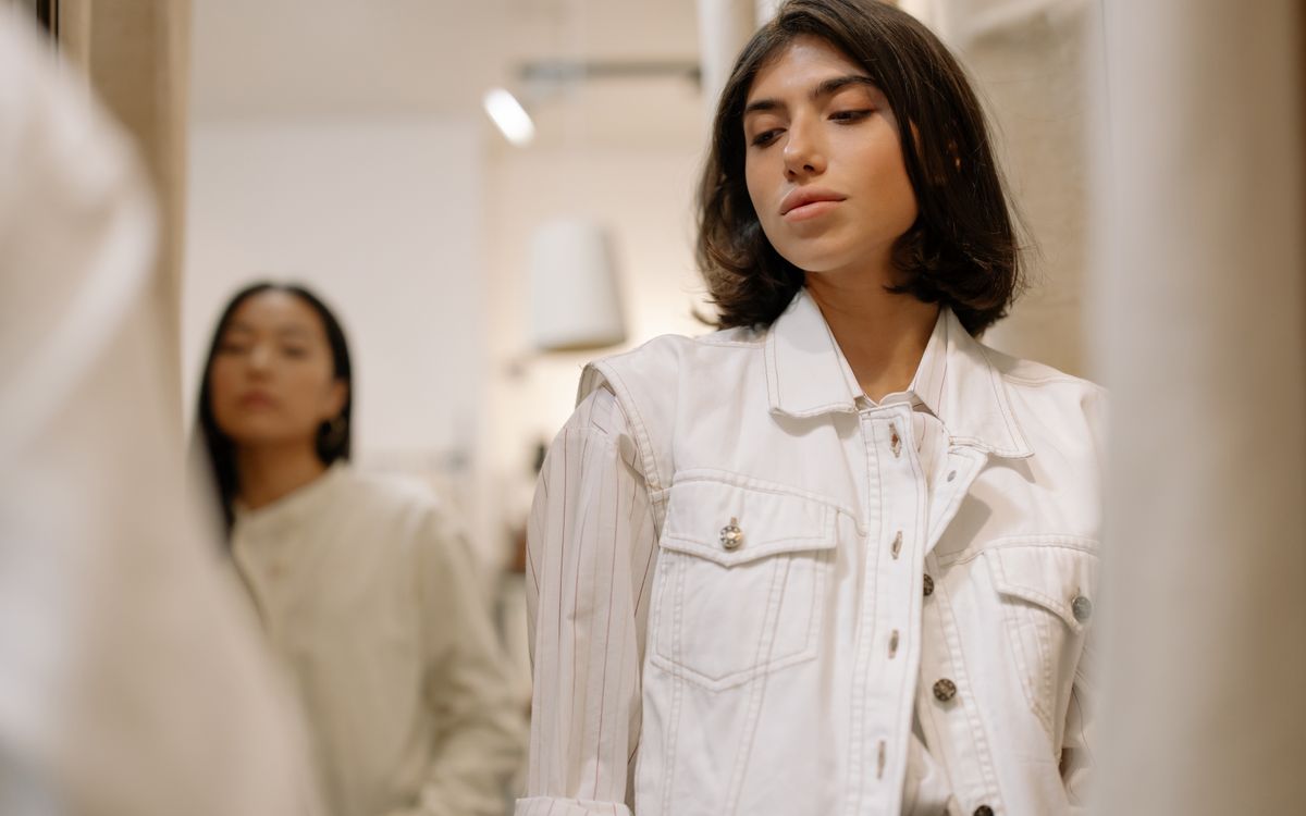 Two people browsing and trying on clothing in a modern fashion store dressing room