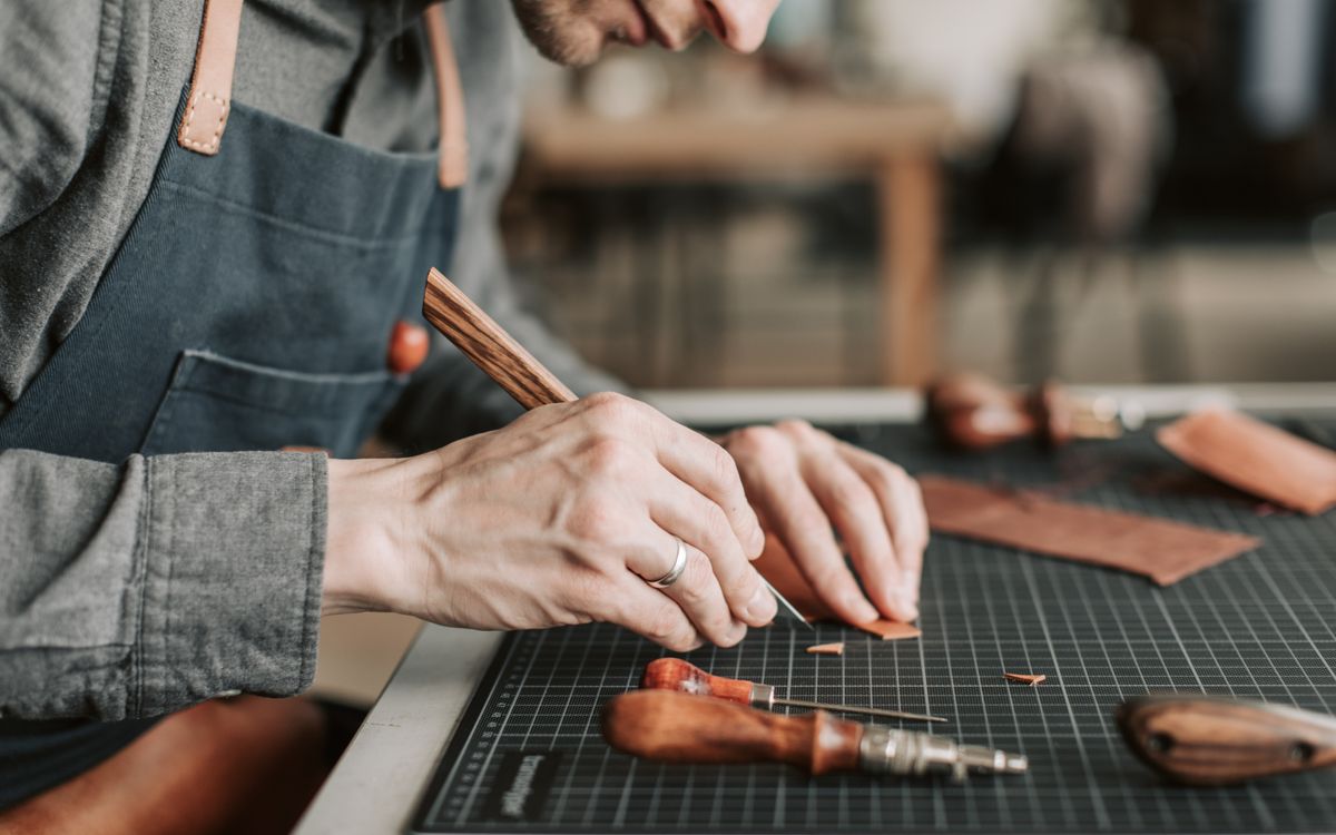 Close-up of an artisan skillfully crafting leather goods by hand in a workshop environment