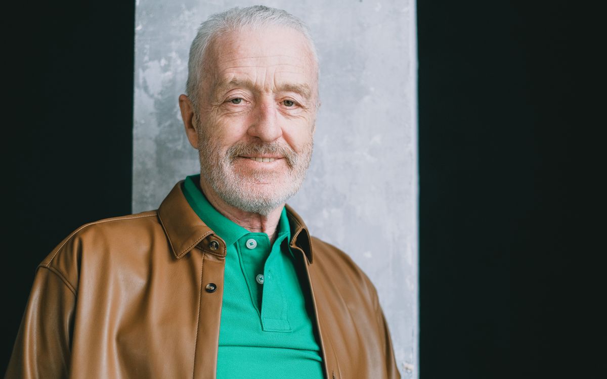 Close-up portrait of a smiling senior man in a leather jacket, indoors