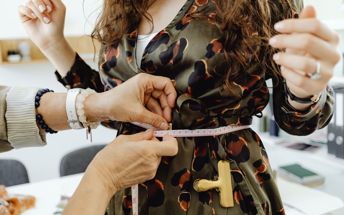 A fashion designer measuring fabric with a tape measure for a precise fit