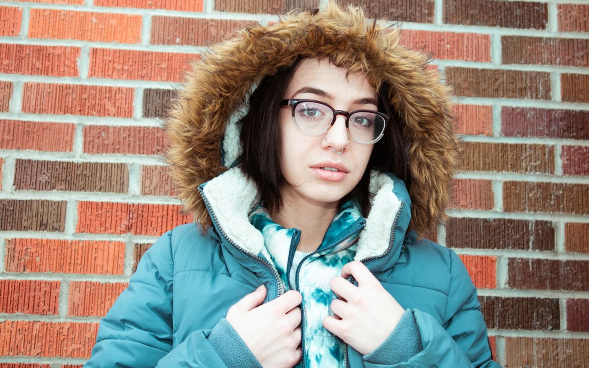 Portrait of a woman wearing glasses and a fur-trimmed leather jacket