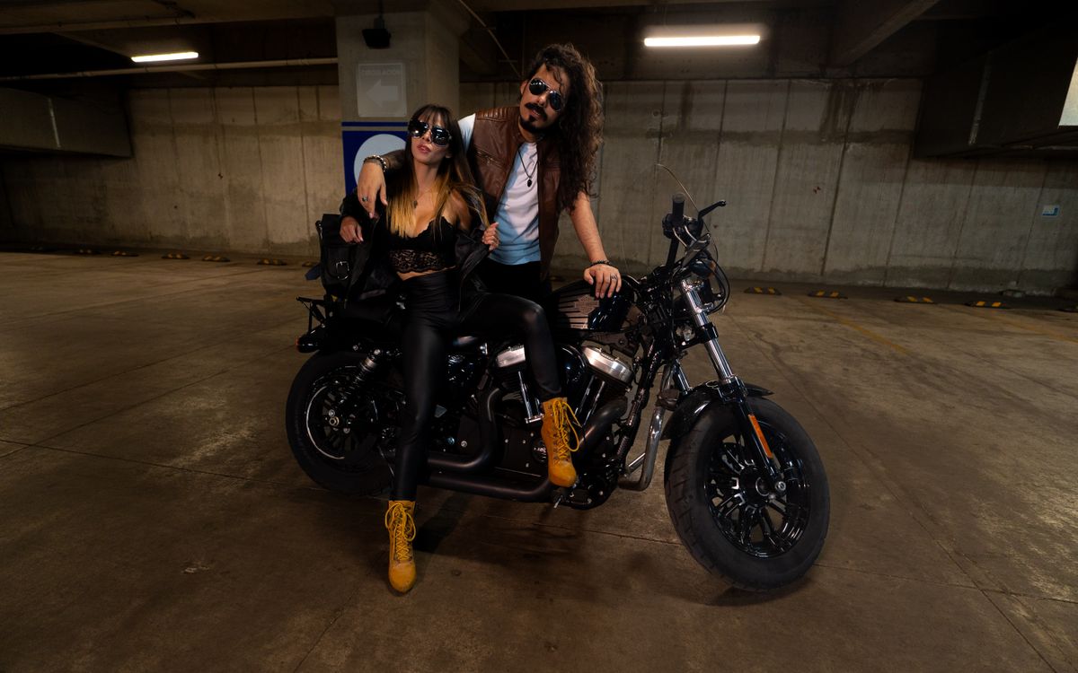 Stylish couple in leather outfits posing with a motorcycle in a garage