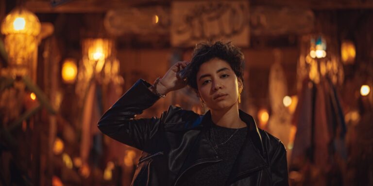 Woman in a black leather jacket standing outdoors in natural evening light