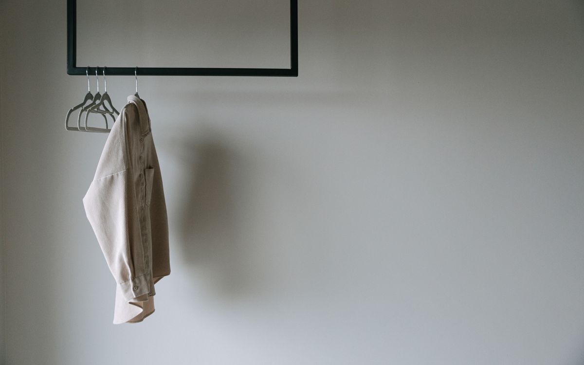 A garment hanging on a simple metal rack in an airy, well lit room