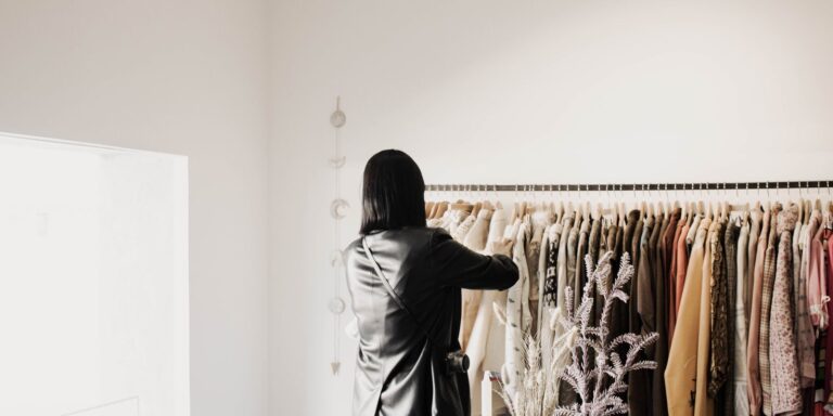 A woman browsing leather jackets on a rack in a bright, stylish boutique