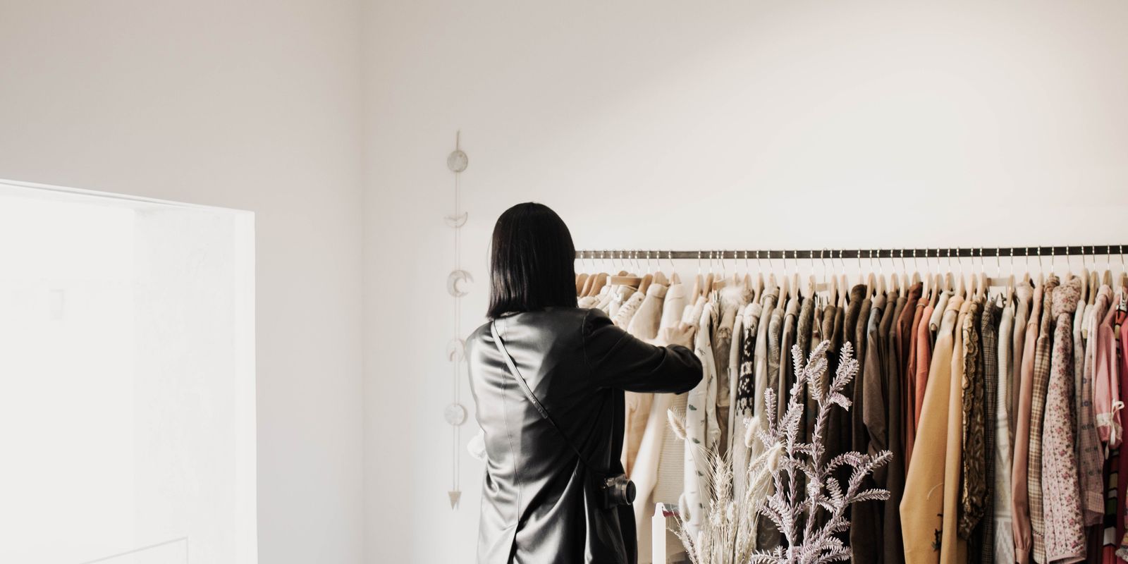 A woman browsing leather jackets on a rack in a bright, stylish boutique
