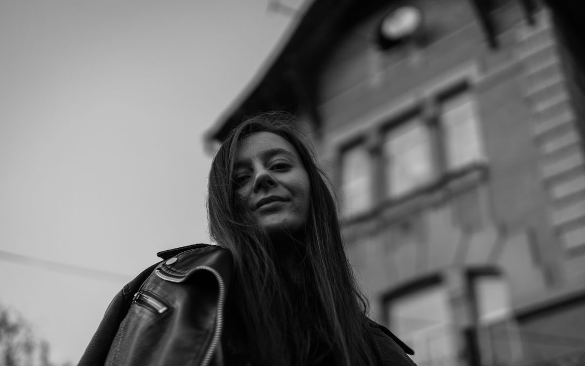 A woman smiling in a leather jacket outdoors, black and white portrait
