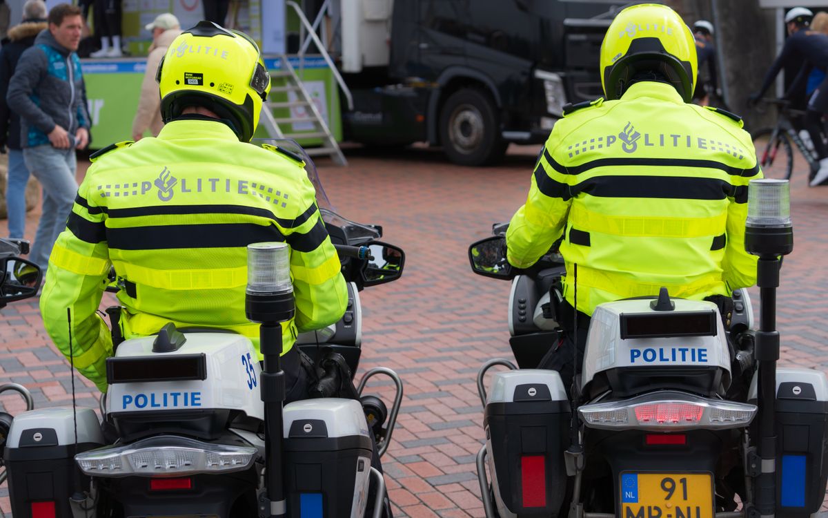 Two police officers in bright uniforms patrolling a public event on motorcycles