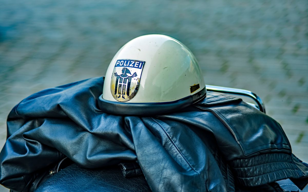 Retro police helmet with insignia resting on a leather jacket outdoors