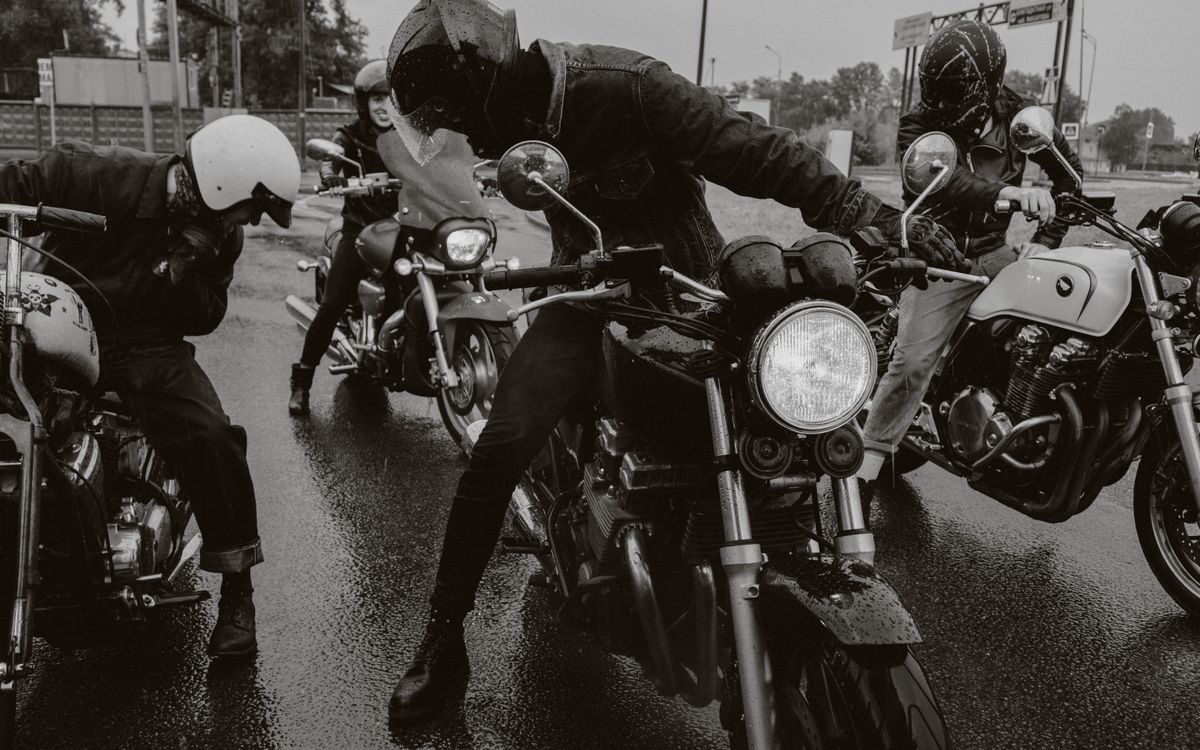 A group of motorcyclists riding along a wet road