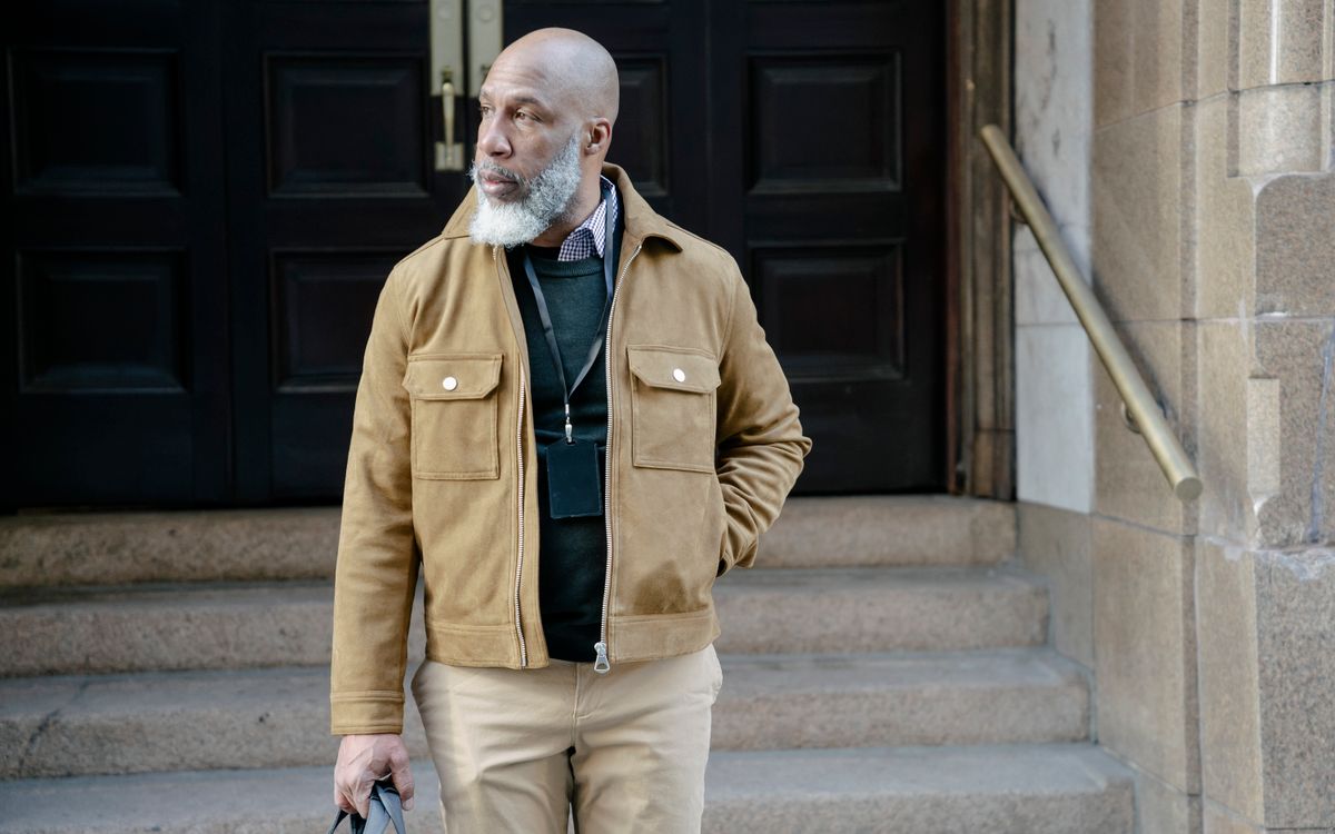 Man with a beard wearing a stylish brown jacket outdoors by stairs, showing a soft matte finish