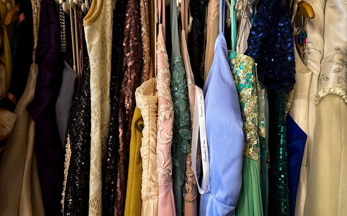 A rack of vintage jackets and clothing hanging in a secondhand store