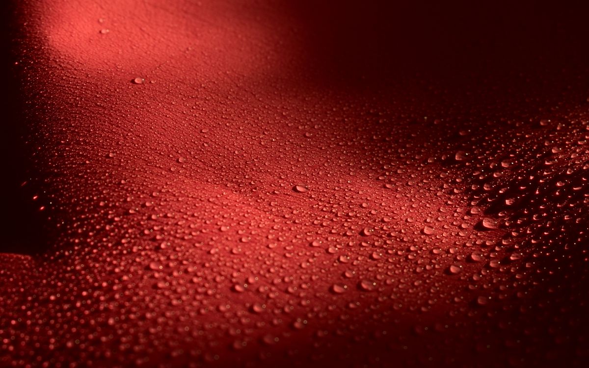 Water droplets scattered across a textured leather-like surface, catching the light