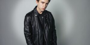Portrait of a young man in a stylish black leather jacket against a gray backdrop