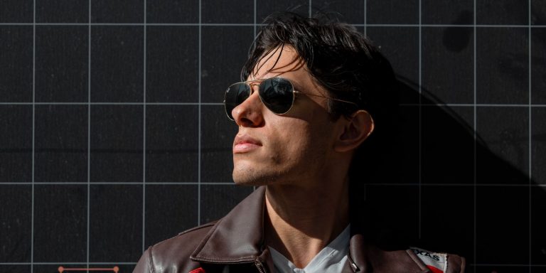 Portrait of a man in sunglasses and a leather jacket against a dark background