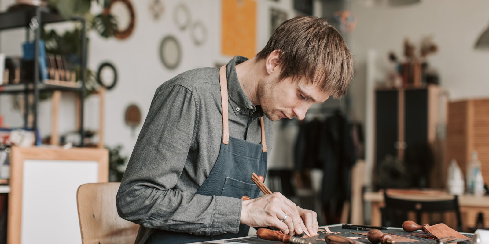 A skilled artisan crafting leatherwork by hand at a workshop table