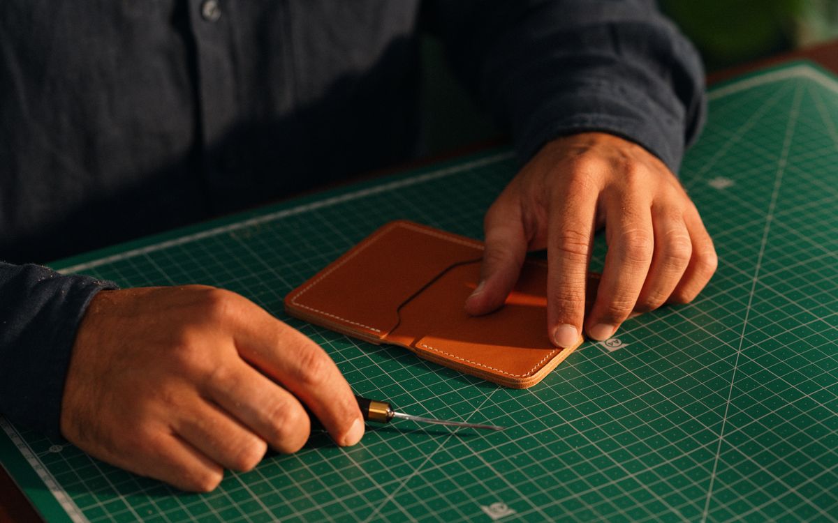 Close-up of hands crafting a leather piece on a workbench