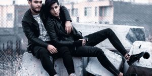 A stylish couple in matching leather jackets sitting together on urban concrete blocks