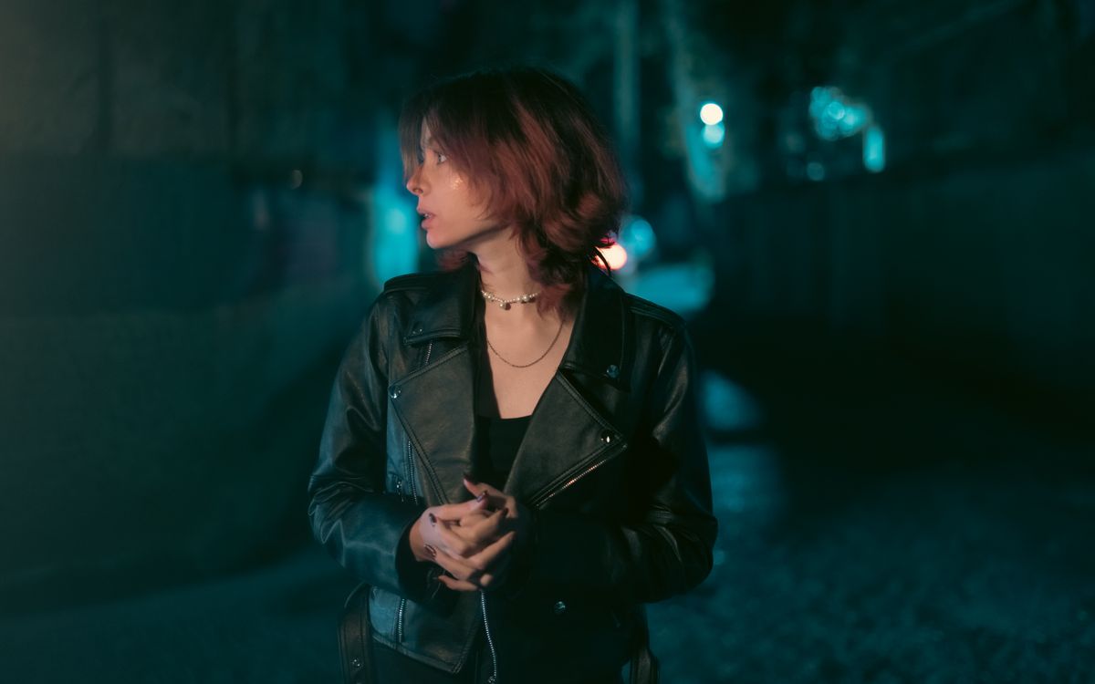 A woman wearing a leather jacket standing confidently in an urban setting