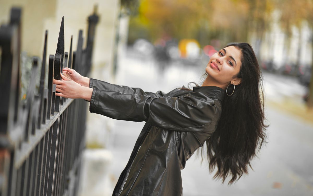 A fashionable woman smiling in a leather jacket outdoors