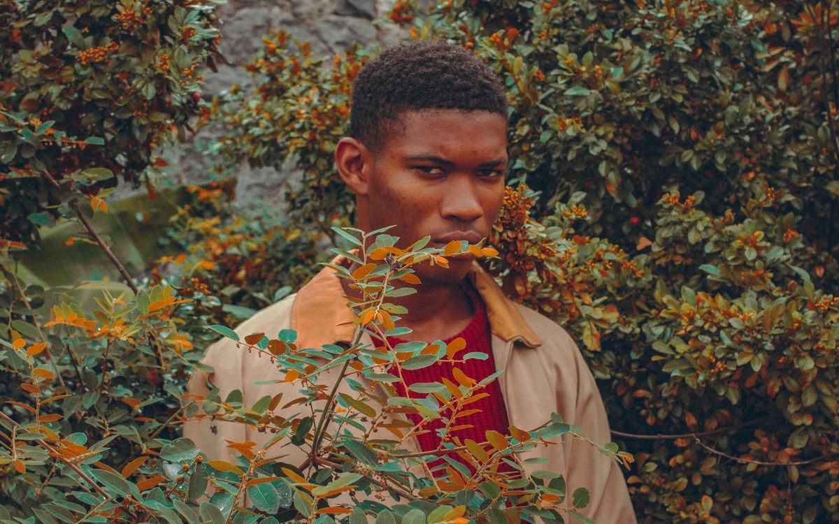 A thoughtful man photographed among warm autumn leaves in a brown leather jacket