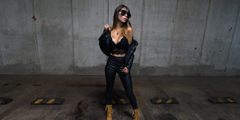 A stylish woman in a black leather jacket posing confidently in an urban street