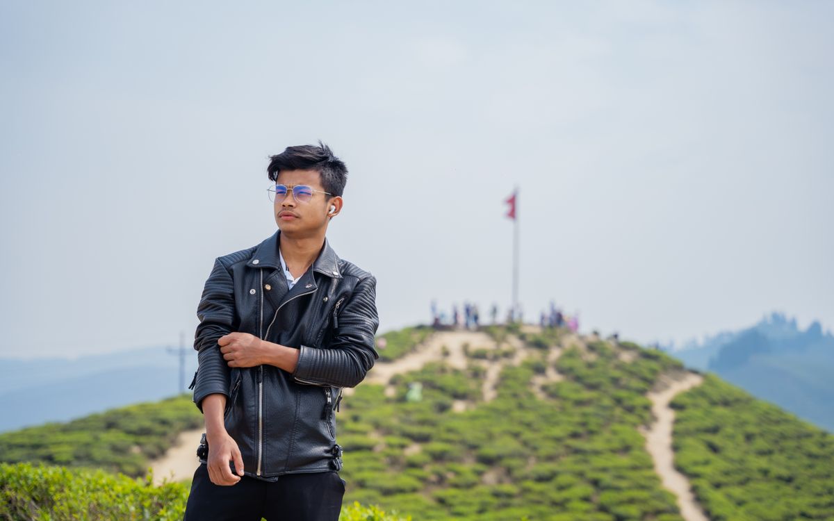 A confident man wearing a brown leather jacket outdoors