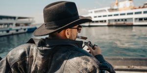 A man wearing a worn vintage black leather jacket on a city street